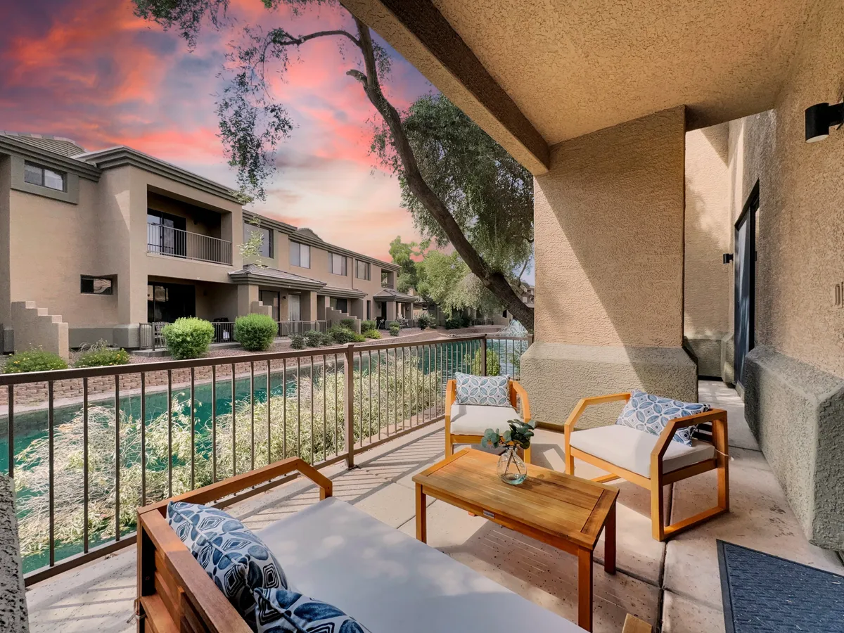 A serene outdoor seating area overlooking a tranquil water feature at sunset, surrounded by lush greenery. The scene invites quiet relaxation, with comfortable chairs arranged for enjoying the peaceful view and gentle evening light reflecting off the water.