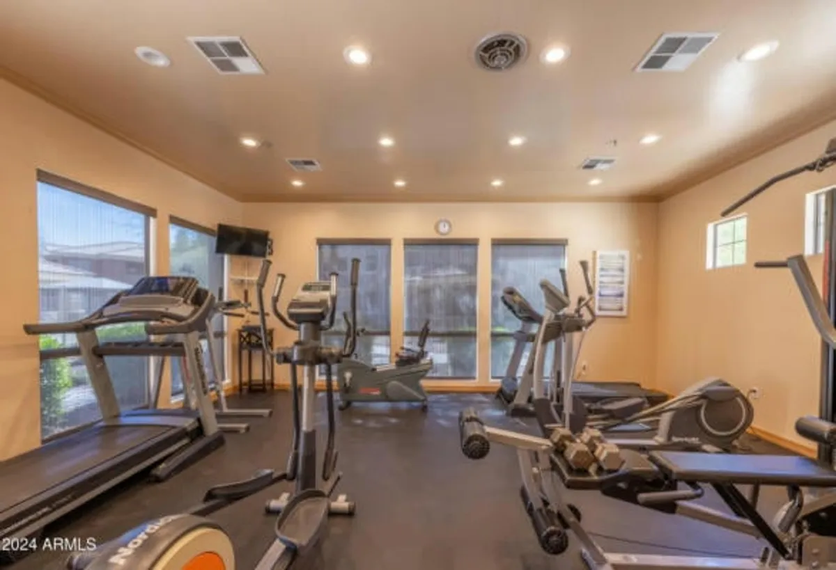 A sleek, well-equipped fitness center with treadmills and elliptical machines positioned in front of large windows, allowing natural light to flood the room. The atmosphere is energetic and inviting, suitable for both solo workouts and group fitness sessions.